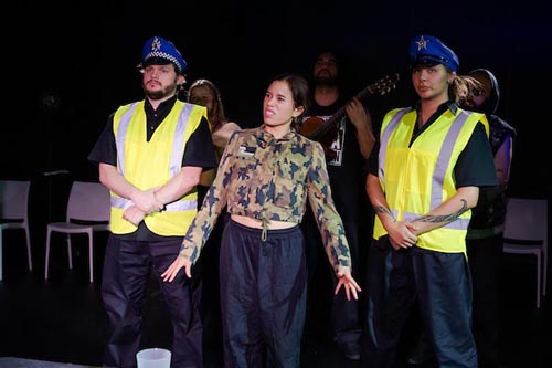 Connie is arrested by two policemen wearing high-vis yellow jackets